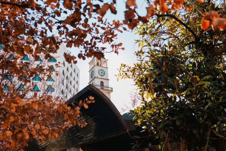 De klokkentoren van Tirana tussen herfstbladeren