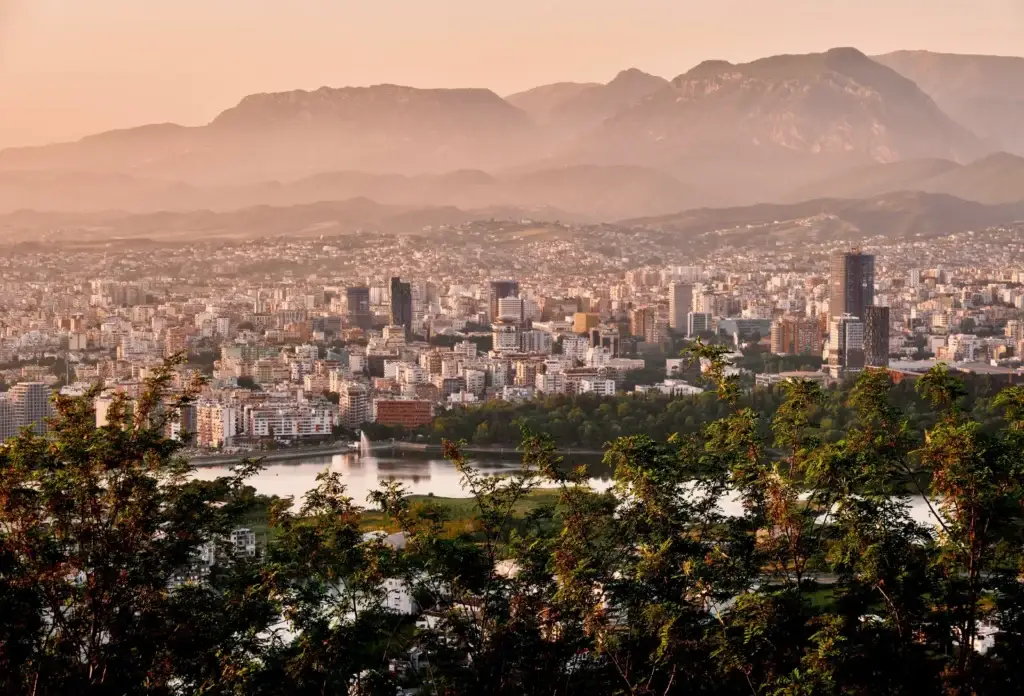 Tirana vanuit de lucht bij zonsondergang met de bergen op de achtergrond